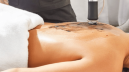 Esthetician performing Geneo full body facial treatment on a woman's back.