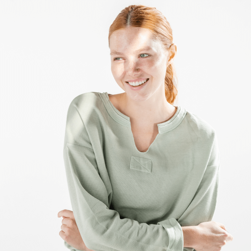 Woman in green shirt with beautiful, glowing skin smiling